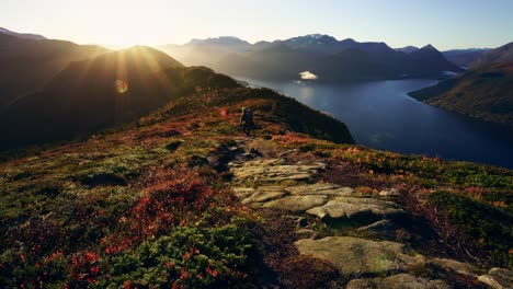 wide shot of a traveler walking down a mountain ridge in a clear and colorful sunrise. majestic landscape.