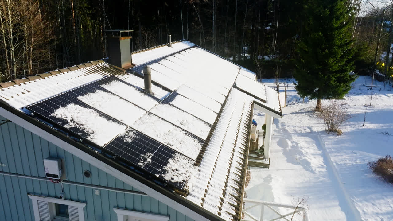 retiro aéreo sobre el derretimiento de paneles solares en un techo de casa nevado, día de invierno