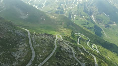 aerial view of a winding mountain road snaking through a lush alpine landscape. the dramatic switchbacks and rugged terrain highlight the elevation and natural beauty of the high-altitude environment