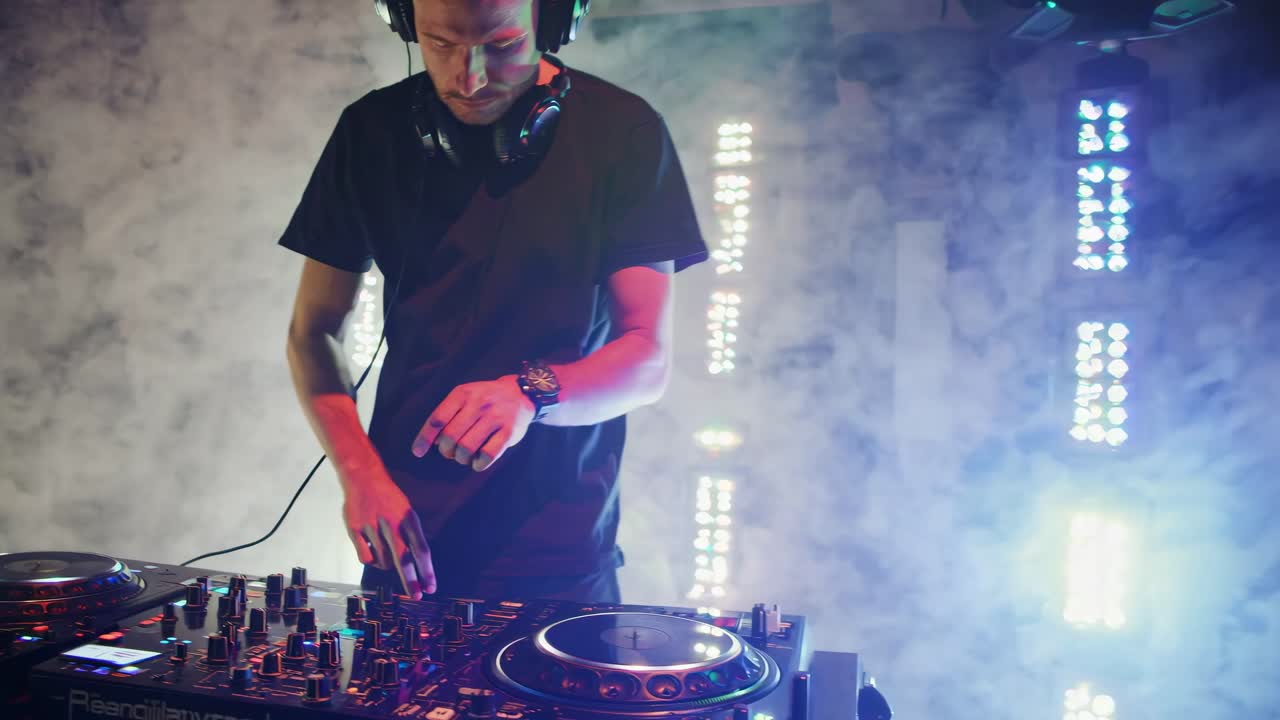 DJ performing in a smoky club with neon lights, captured from a side angle