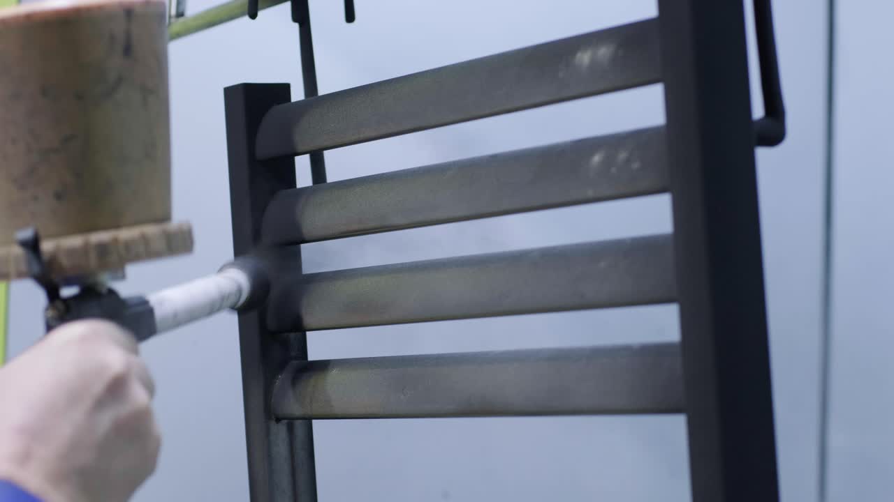 un trabajador pinta una estructura metálica de acero inoxidable con una pistola de pulverización de aerógrafo. método de pintura en seco.