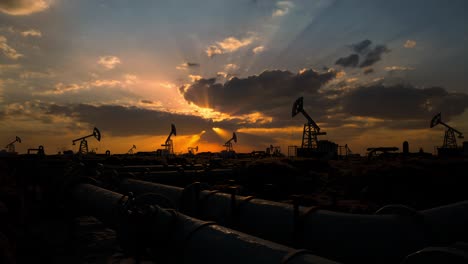 pipeline and working oil pump jacks in a against sunset extracting crude oil. pumping fossil oil is one of the methods of energy generation from renewable energy sources