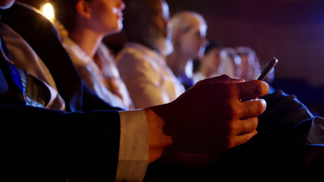 hombre de negocios usando teléfono móvil en un seminario de negocios en el auditorio 4k
