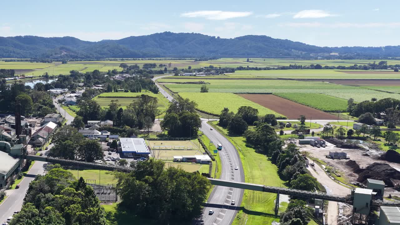 Aerial footage captures lush fields and roads in Murwillumbah, NSW, under bright daylight with distant mountains