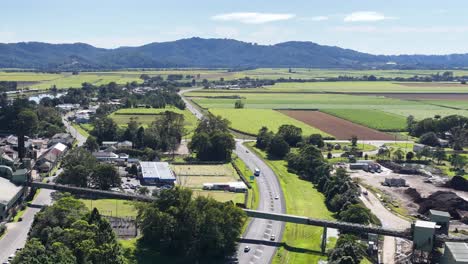 aerial footage captures lush fields and roads in murwillumbah, nsw, under bright daylight with distant mountains
