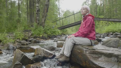 mujer relajándose junto a un arroyo de montaña