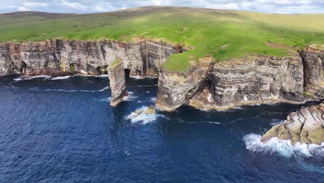 aerial view of sea stack and steep cliffs on coastline of scotland uk, cinematic drone shot