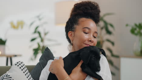 woman cuddling a black puppy on a sofa