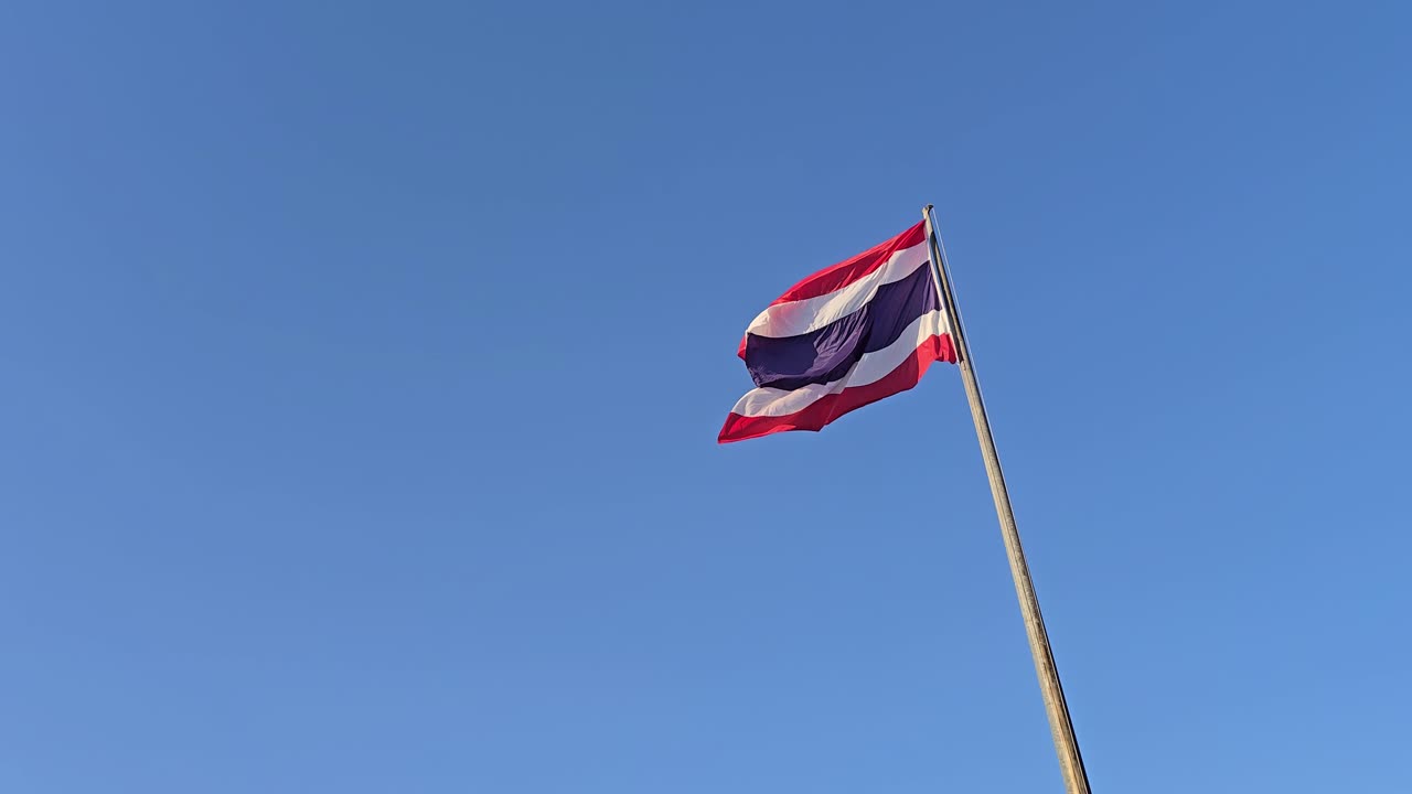 Bandiera nazionale thailandese che sventola con vento calmo contro un cielo azzurro limpido, inquadratura ampia