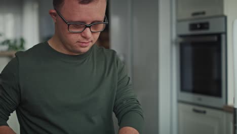 Tilt-up-of-adult-caucasian-man-with-down-syndrome-washing-dishes-at-home