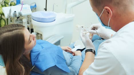 the dentist shows the patient a mock dentition with removable dentures and pins