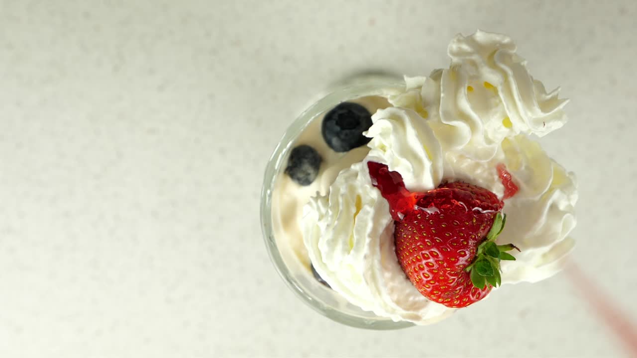 식욕을 돋우는 슬로우 모션으로 크림 같은 디저트에 떨어지는 빨간 딸기 시럽