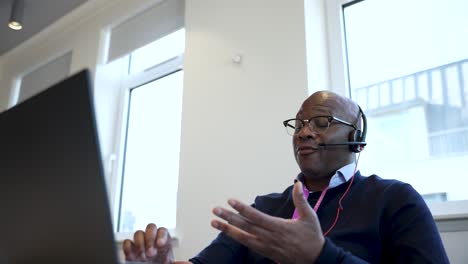 A-professional-individual-is-seen-working-diligently-on-a-laptop-while-wearing-a-headset