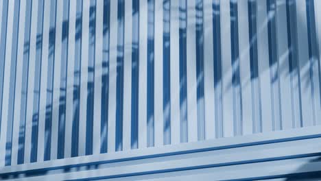 blue metal panels with shadows of tropical leaves. abstract architectural detail. close-up photography with copy space for design and print