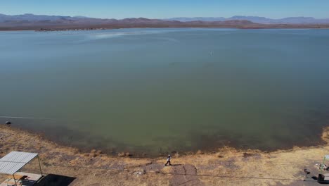 Vista-Aérea-De-La-Persona-Que-Camina-En-La-Costa-Del-Lago-Balmorhea,-Texas-Usa-En-El-Soleado-Día-De-Primavera