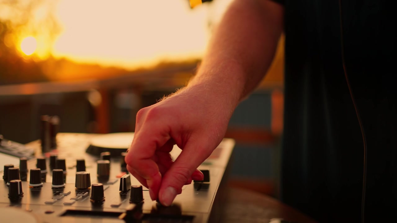 DJ Mixing Music on Controller at Sunset