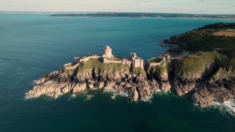 drone shot with fort la latte, chateau de la roche guyon in the foreground and revealing the emerald coast in the background near cap frehel in brittany, france on a sunny day of summer