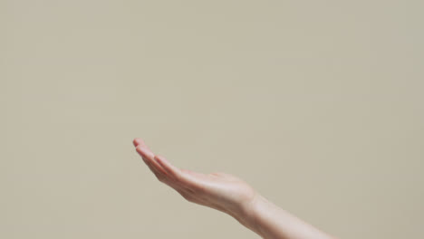 hand of asian woman on beige background with copy space, slow motion