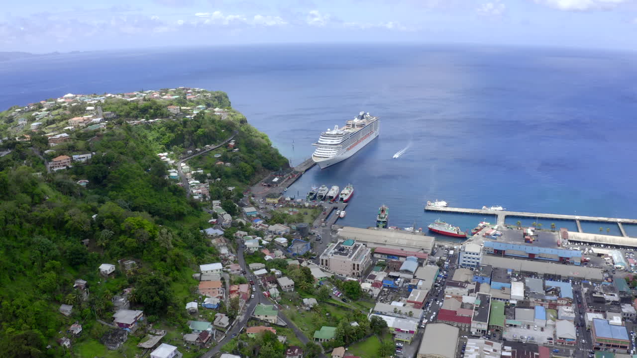 세인트 빈센트의 산에서 내려오는 드론 - 킹스타운은 놀라운 도시 구호, 도시의 녹색 초목, 대형 유람선이 정박해 있는 크루즈 및 페리 항구를 향해 날아갑니다.