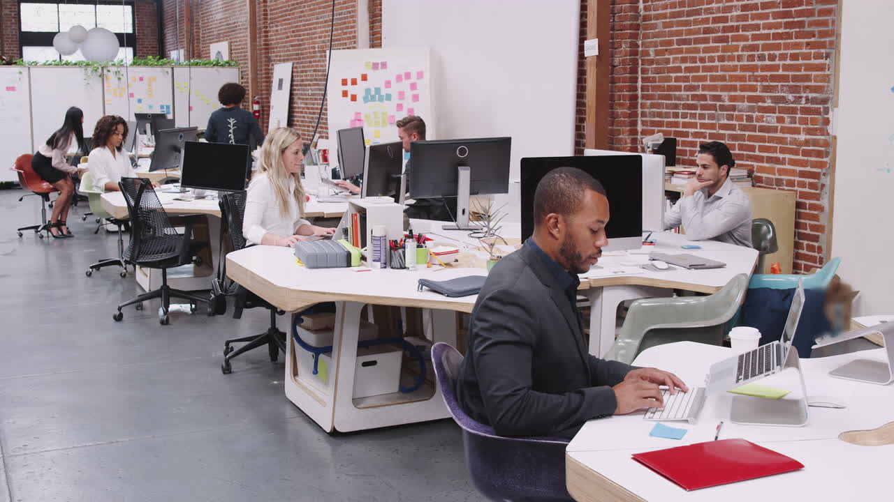 Crane Shot Of Business Team Working At Desks In Modern Open Plan Office