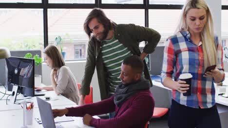 diversas personas de negocios de pie hablando usando una computadora portátil en una oficina moderna
