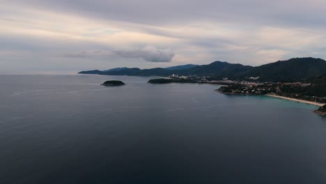 Slow-drone-flight-over-an-ocean-with-mountains,-islands,-beaches-and-boats-in-the-background-in-4K-on-the-island-of-Phuket