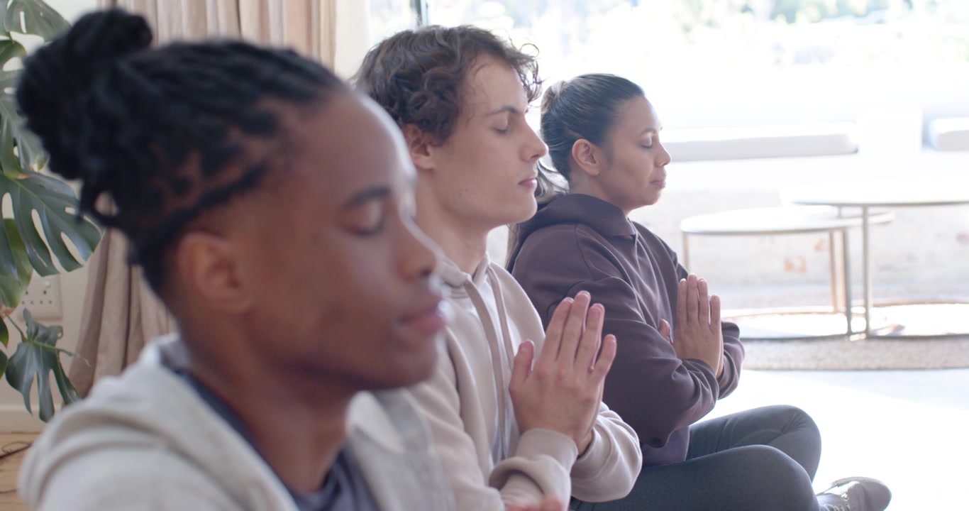 Middle peer bringing palms, urging African American man practicing meditation by window, copy space