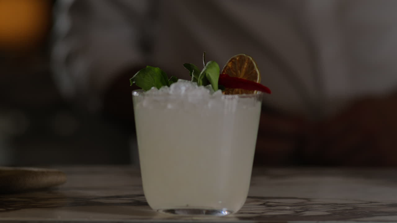 el camarero presenta una margarita con chile tailandés y albahaca.