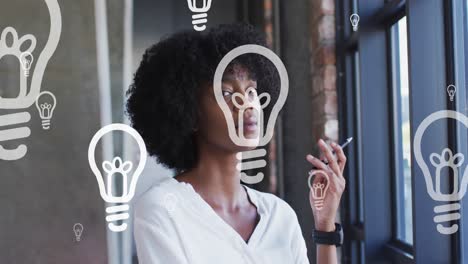 Animation-of-portrait-of-lightbulb-icons-over-african-american-businesswoman-thinking