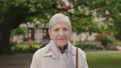 portrait of senior elderly caucasian woman in park looking at camera wearing scarf