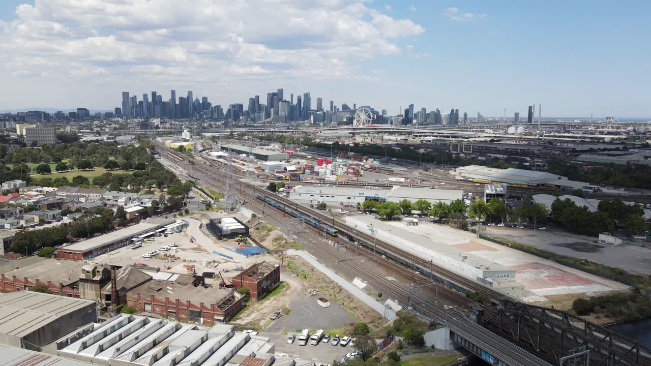 Aerial drone over industrial area, panning up to reveal Melbourne city skyline