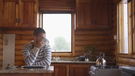 caucasian man spending time at home, drinking a beverage, looking at the window