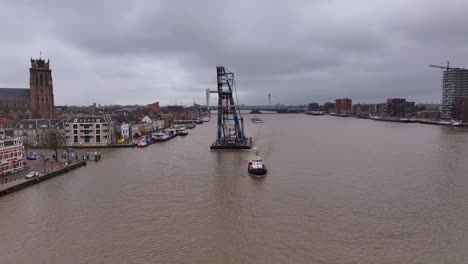 matador crane towers over the water and the small tug boat below