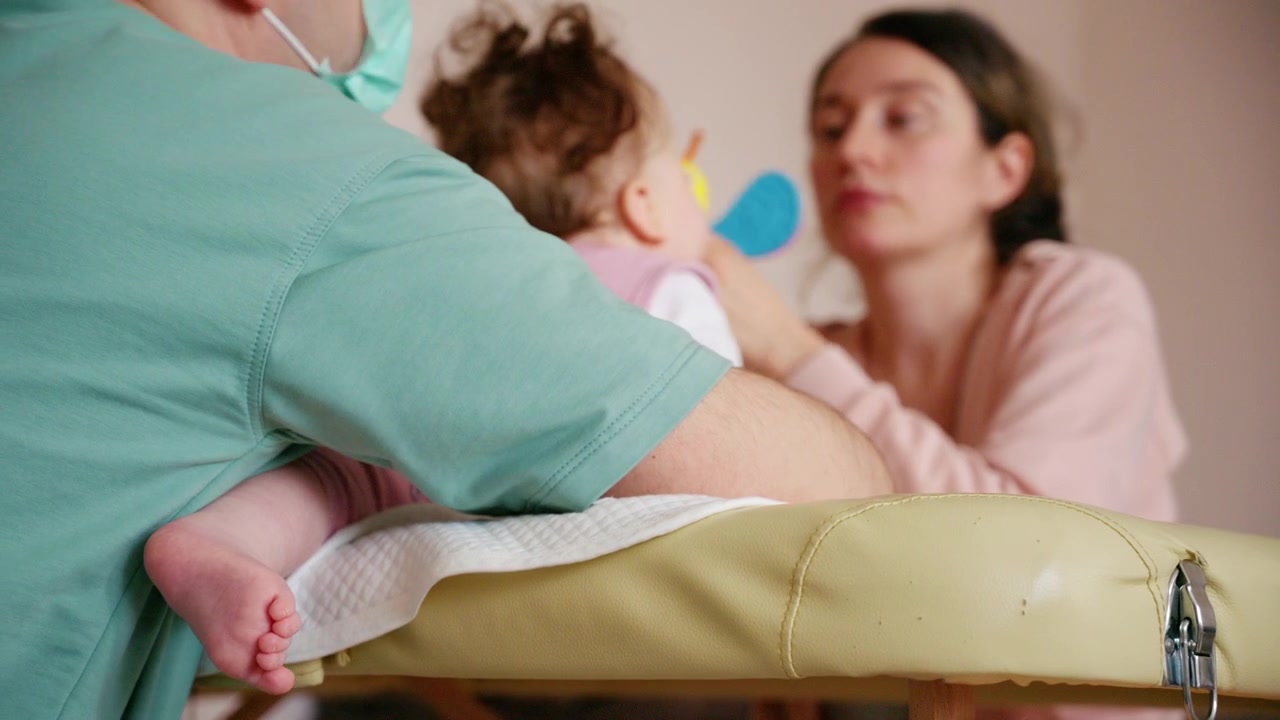 Un sonaglio colorato per neonati viene delicatamente presentato a un neonato, mentre il caregiver esegue esercizi di mobilità