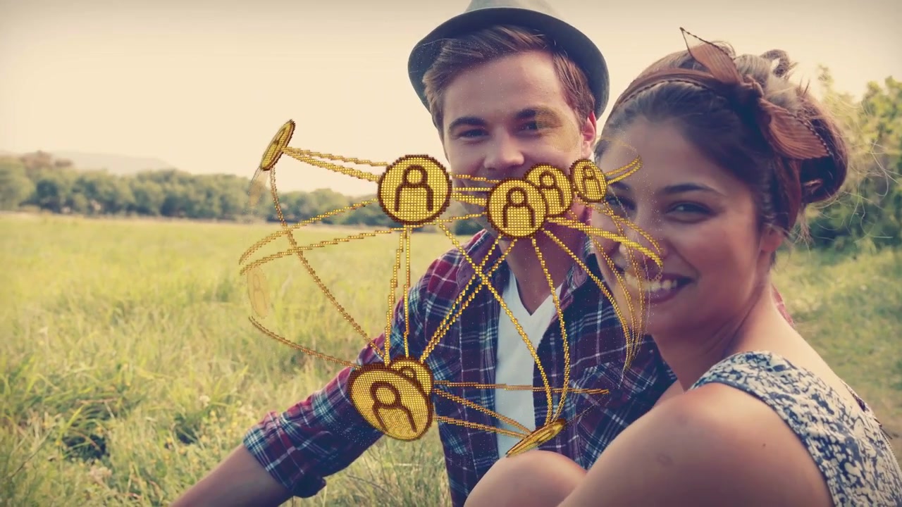 Coppia che si appoggia in un prato mentre appaiono gettoni d'oro, che orbitano tra di loro, visualizzando una rete sociale.