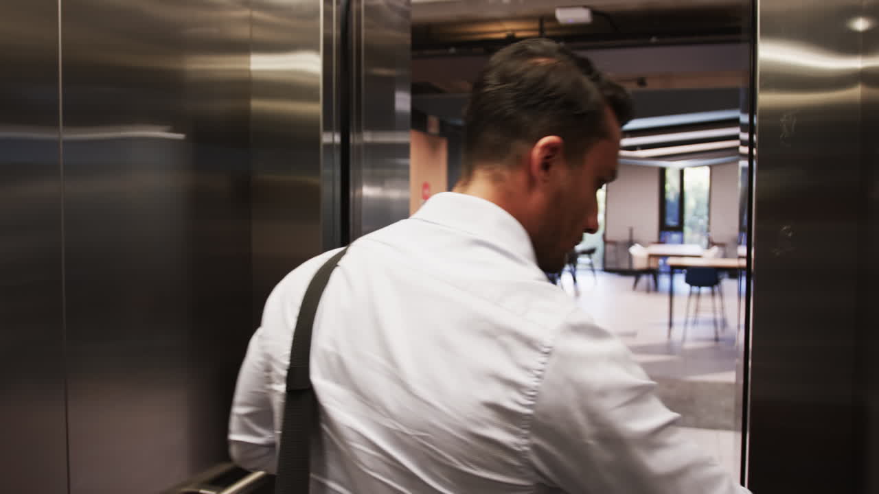 Entering elevator, businessman in white shirt carrying black bag, heading to office