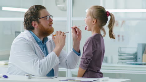 pediatrician checking throat of little girl