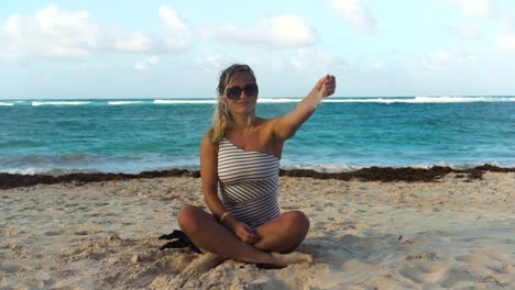 a girl is sitting on the beach playing with sand