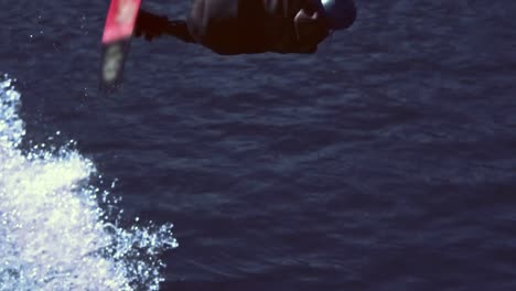 Athletic-man-after-trick-with-jump-on-wakeboard-plunging-into-water