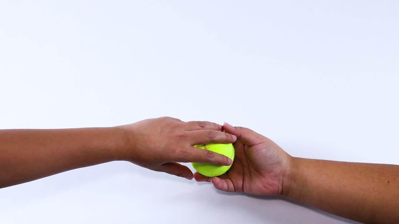 Two hands exchanging a tennis ball