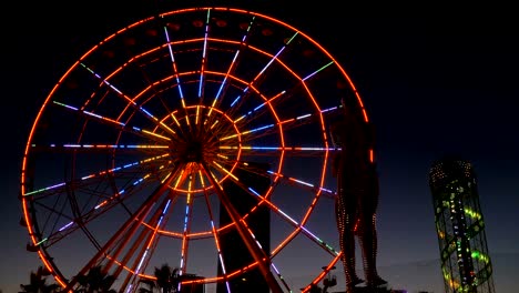 statue of ali and nino on a background ferris wheel at night on the embankment of batumi, georgia