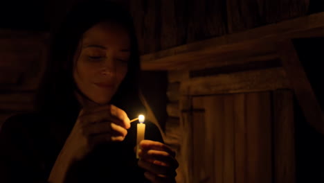 woman lighting a candle in a cabin