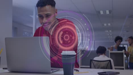 animación de escáner redondo contra hombre biracial sonriendo mientras usa una computadora portátil en la oficina.