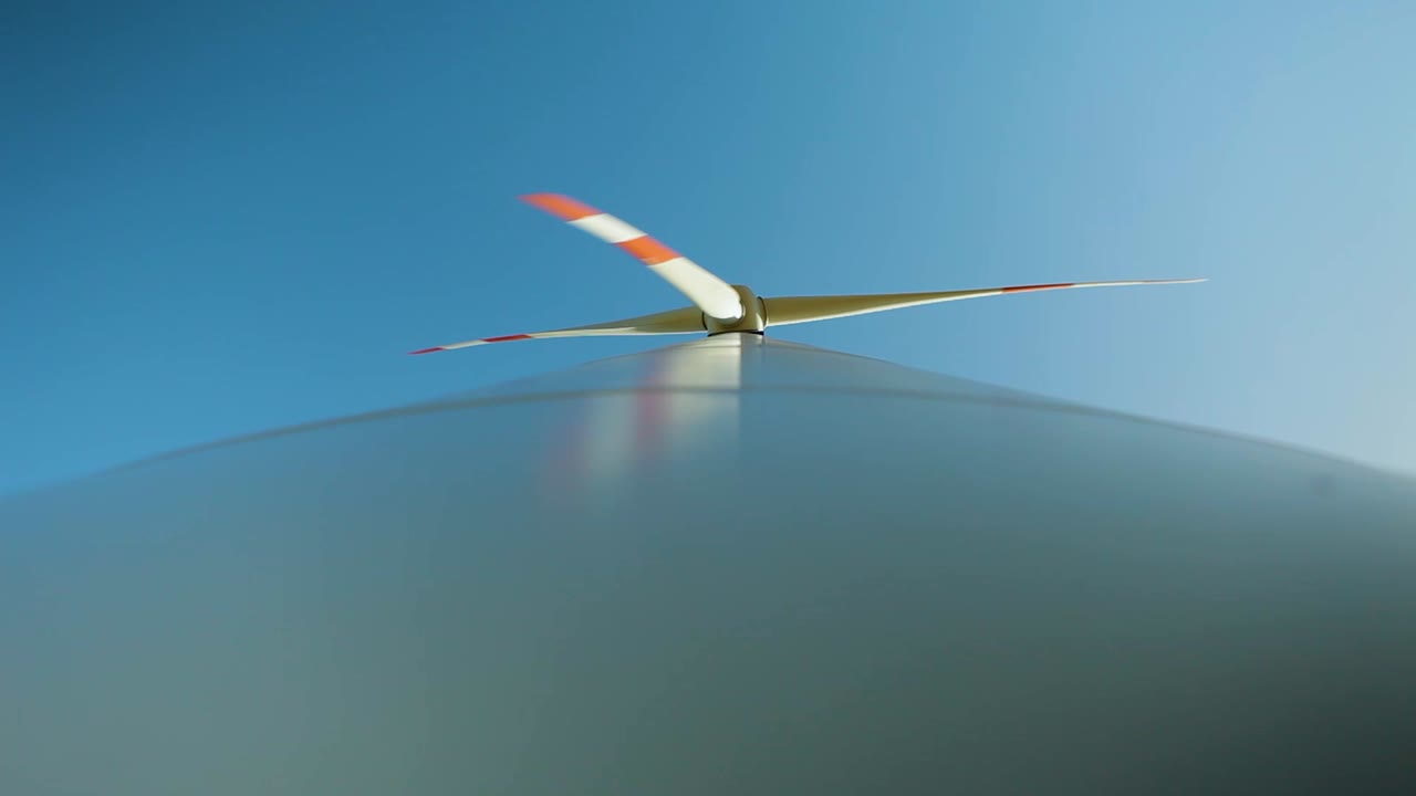깨한 파란 하늘을 배경으로 풍력 터빈 블레이드의 동적 클로즈업으로 지속 가능한 에너지를 보여줍니다.