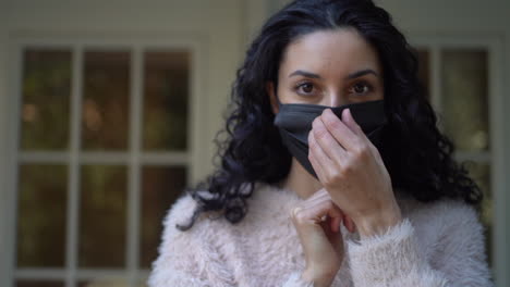 young latina woman makes sure her face mask fit properly over her nose - isolated