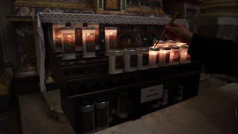 woman lighting candles in pot light in a church. praying for god concept.
