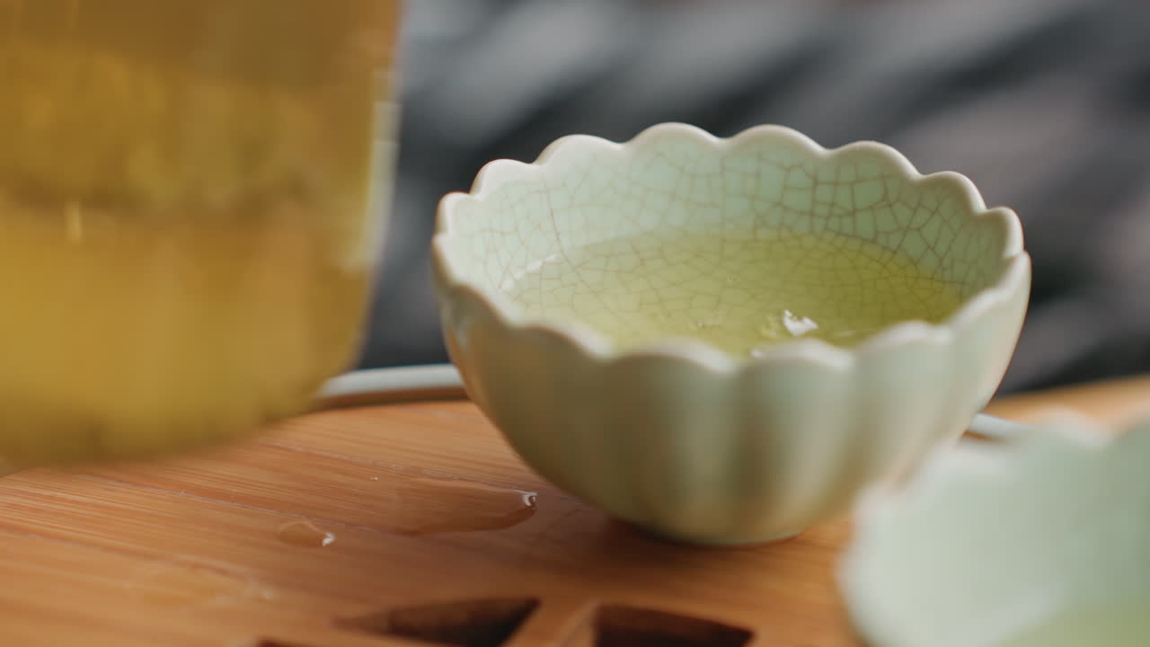 豪華な空間で静かに行われる職人技のお茶の注ぎ、高級ホテルのスパ環境でのリラックスできるお茶の提供、豪華なホテルのスパ環境で装飾的なカップに温かいお茶が注がれる穏やかな情景。