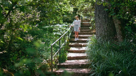 woman walking forest stairs at summer vacation trip. girl going downstairs park