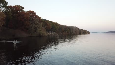 colorful fall foliage lines the edge of lake wisconsin as calm water mirrors the trees. this peaceful scene captures the beauty of seasonal change in the midwest during a still evening.