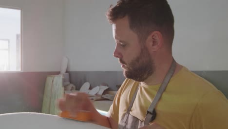 un hombre que hace tablas de surf en su taller
